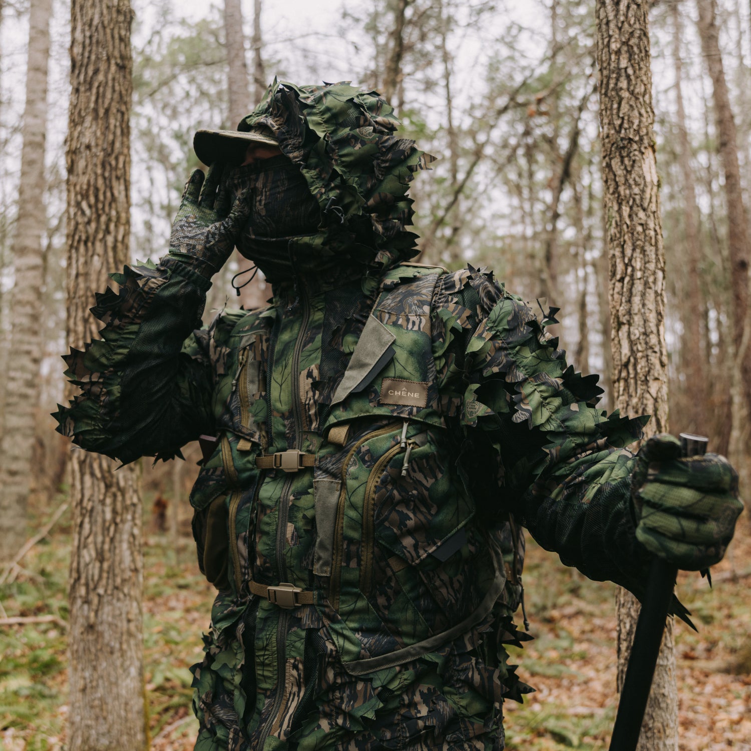 Person in full camouflage gear standing in a forest