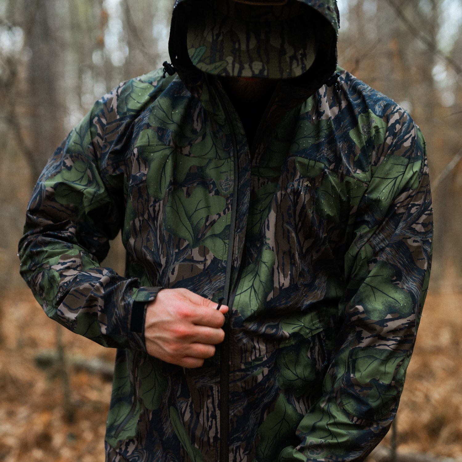 Person wearing a camouflage jacket in a forest setting